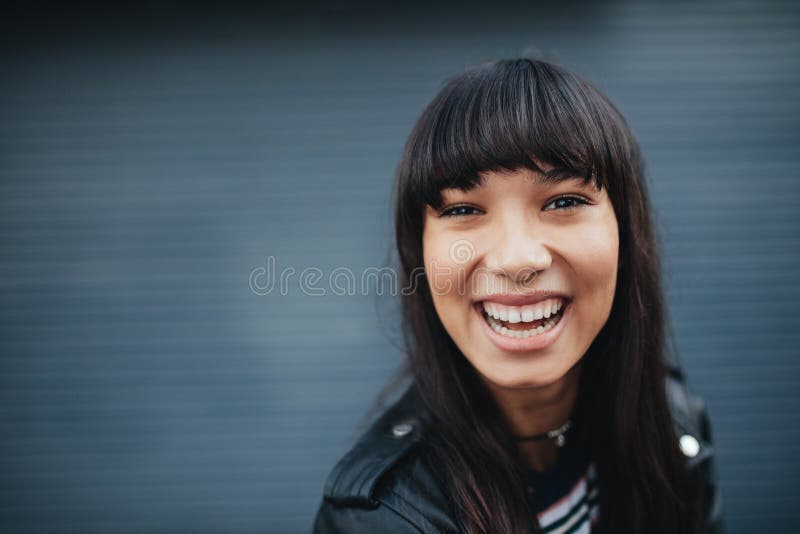 Jovem mulher que ri contra o fundo cinzento imagens de stock Jovem mulher que ri contra o fundo cinzento imagens de stock