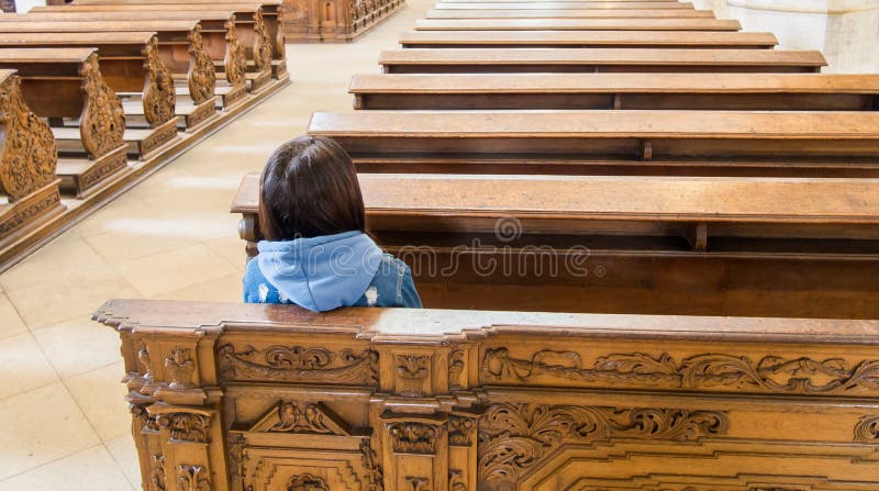 Jovem mulher que senta-se em uma igreja vazia imagem de stock royalty free Jovem mulher que senta-se em uma igreja vazia imagem de stock royalty free