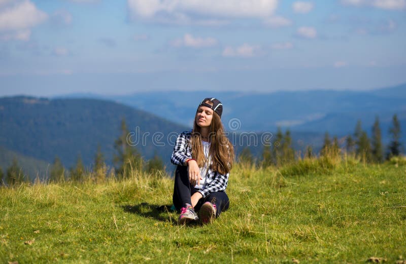 Jovem mulher que senta-se na parte superior da montanha que olha pacificamente em nuvens ao nível do mar da manhã imagens de stock royalty free Jovem mulher que senta-se na parte superior da montanha que olha pacificamente em nuvens ao nível do mar da manhã imagens de stock royalty free