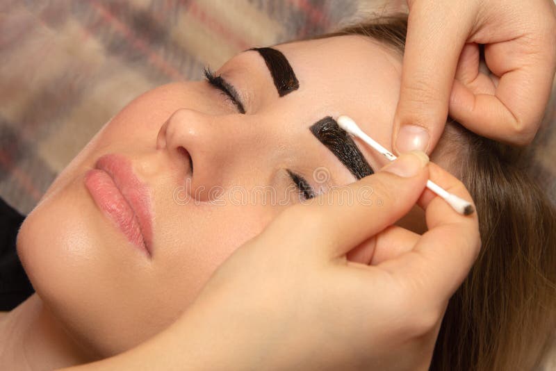 Jovem mulher que tem o procedimento profissional da corre??o da sobrancelha no sal?o de beleza imagens de stock Jovem mulher que tem o procedimento profissional da corre??o da sobrancelha no sal?o de beleza imagens de stock