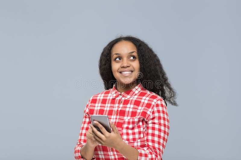 Jovem mulher que usa da menina afro-americano esperta do telefone da pilha o sorriso feliz que olha acima para copiar o espaço foto de stock royalty free Jovem mulher que usa da menina afro-americano esperta do telefone da pilha o sorriso feliz que olha acima para copiar o espaço foto de stock royalty free