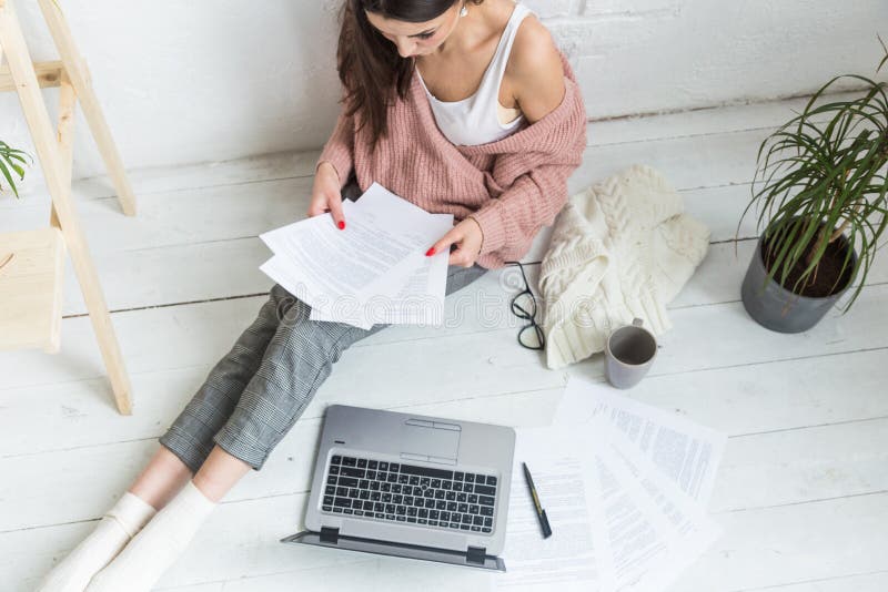 A jovem mulher senta-se no assoalho em um interior escandinavo do apartamento com um port?til, estudando a lei, menina aut?nomo n fotos de stock royalty free A jovem mulher senta-se no assoalho em um interior escandinavo do apartamento com um port?til, estudando a lei, menina aut?nomo n fotos de stock royalty free