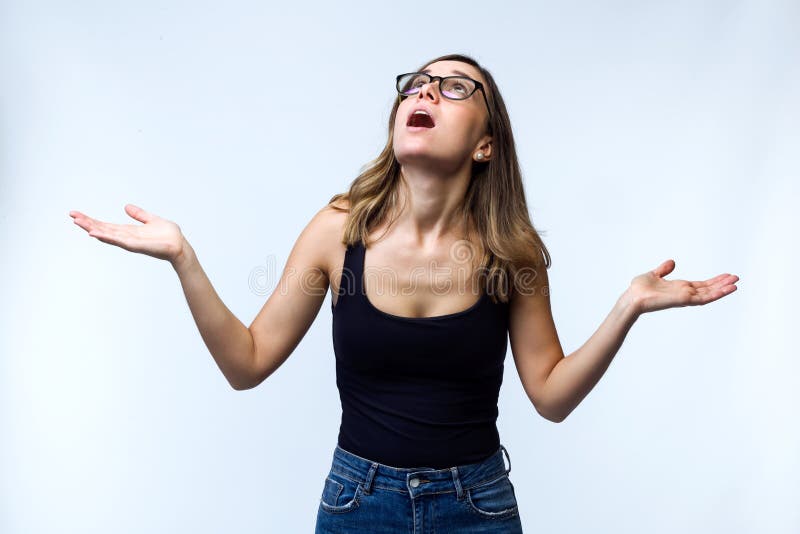Jovem mulher surpreendida bonita com os monóculos que olham ao telhado sobre o fundo branco foto de stock Jovem mulher surpreendida bonita com os monóculos que olham ao telhado sobre o fundo branco foto de stock