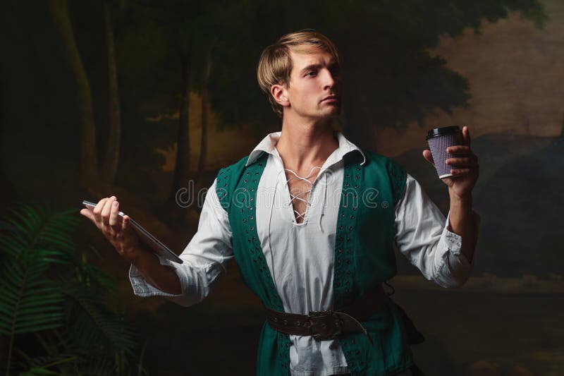 Young man in Renaissance style uses gadgets. Funny duet of medieval style and modern attributes, concept. Young man in Renaissance style uses gadgets. Funny duet of medieval style and modern attributes, concept.