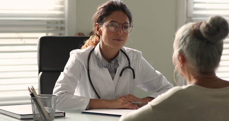 Jovem profissional de medicina geral que consultava a mulher idosa.