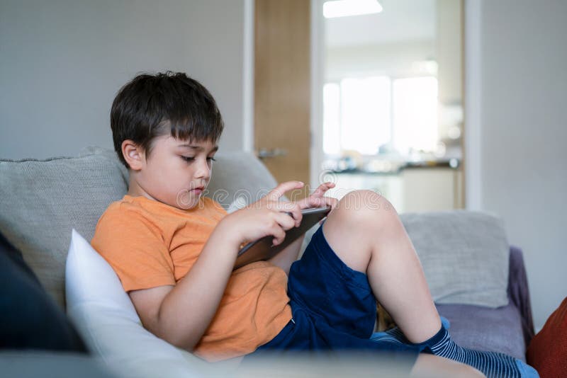 criança jogando jogos online na internet no quarto, retrato de menino  usando tablet digitando ou conversando com amigos de manhã, infância  sentada na cama fazendo lição de casa, criança da escola com