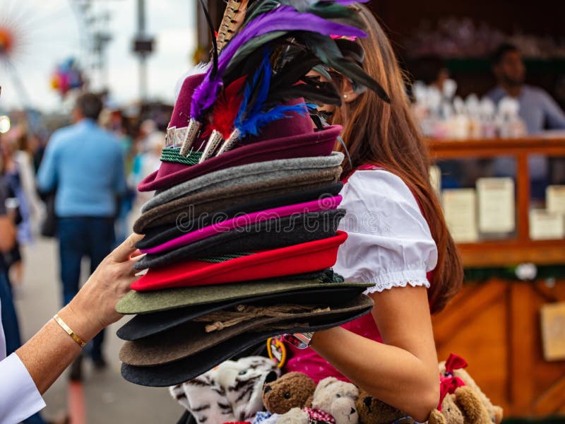 Jovem senhora no traje tirolês que guarda uma pilha de chapéus tradicionais, Oktoberfest, Munich, Alemanha foto de stock Jovem senhora no traje tirolês que guarda uma pilha de chapéus tradicionais, Oktoberfest, Munich, Alemanha foto de stock