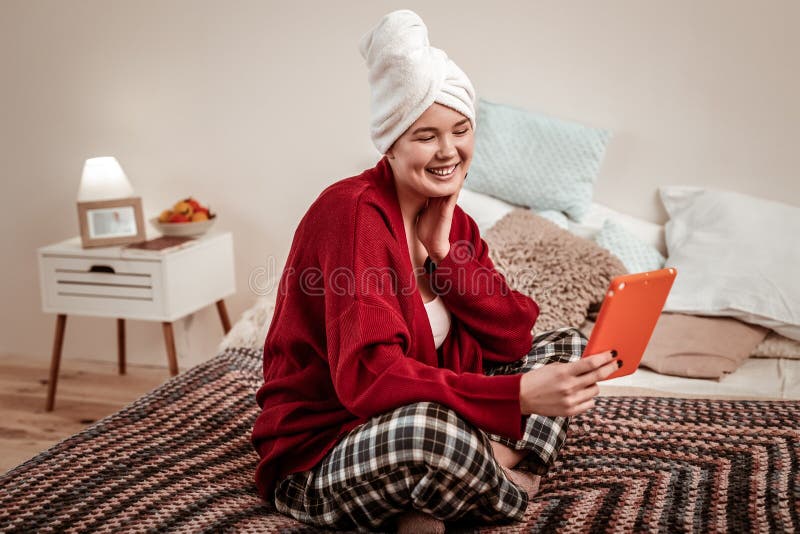 Jovem senhora positiva que olha provocante na câmera da tabuleta imagem de stock Jovem senhora positiva que olha provocante na câmera da tabuleta imagem de stock