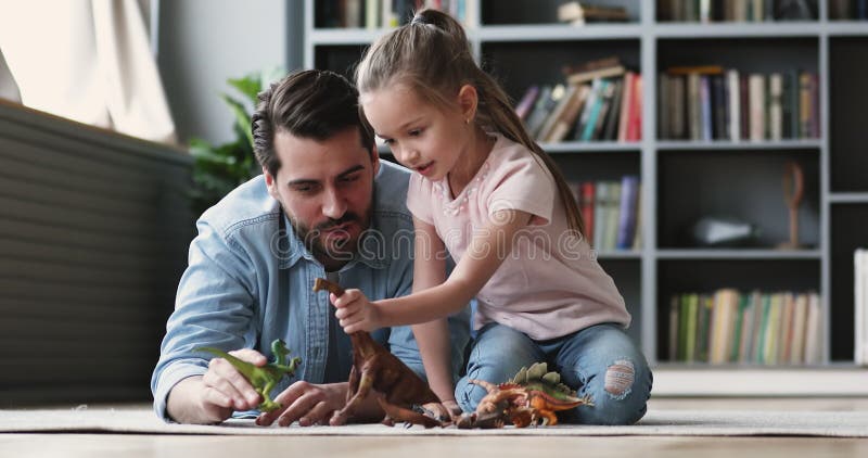 Jovem sorridente e bonito pai brincando de brinquedos com a filha.