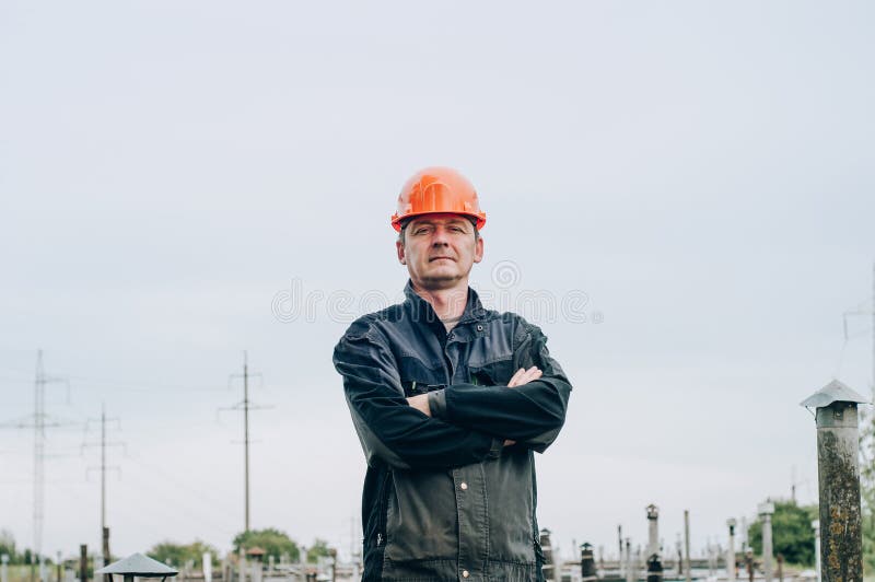 Young construction worker in overalls and orange safety helmet near construction metal coil store. Young construction worker in overalls and orange safety helmet near construction metal coil store.