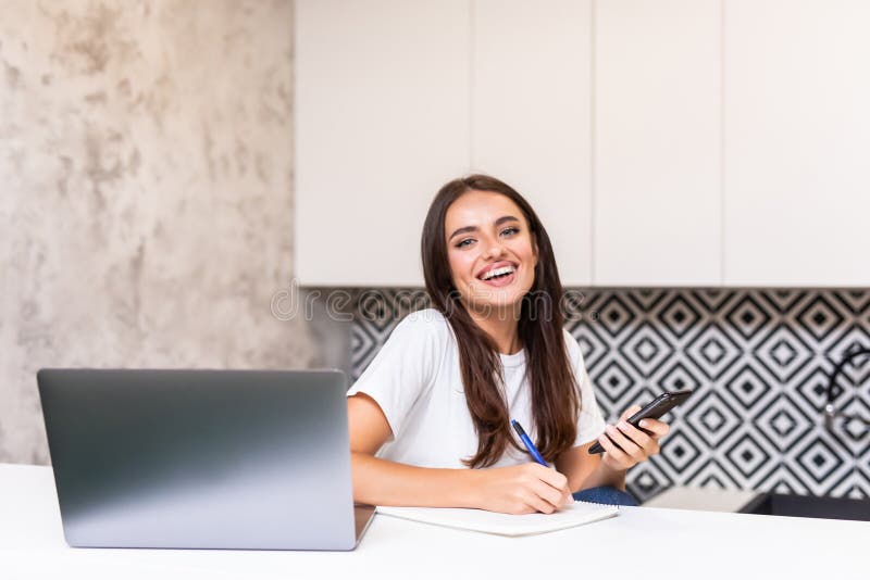 Jovem trabalhadora doméstica. freelancer usa internet e notebook para celular foto de stock royalty free