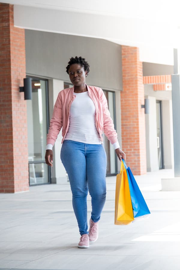 Joven africana caminando con bolsas de compras. Joven africana con ropa informal caminando con sus bolsas de compras