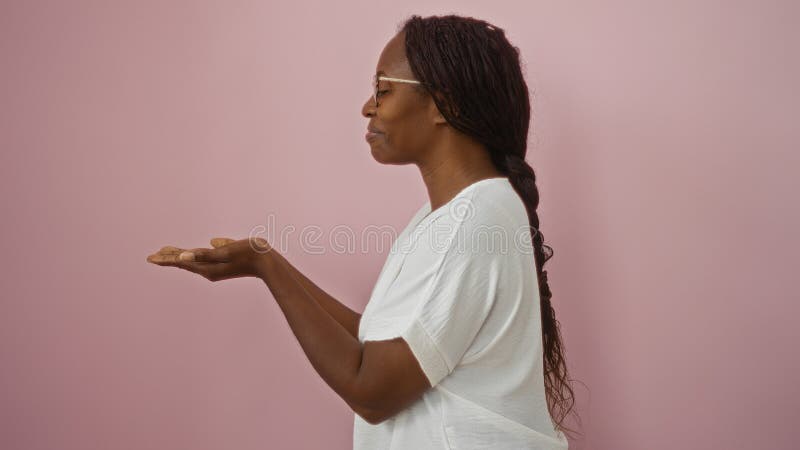 Joven afroamericana aislada sobre fondo rosado extendiendo sus manos hacia delante imágenes de archivo libres de regalías