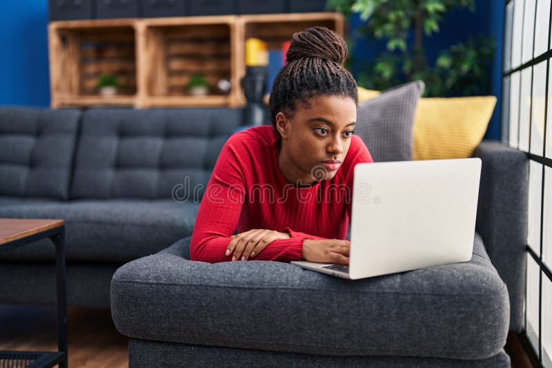 Joven afroamericano con trenzas trabajando usando la actitud de pensar en laptop y expresión sobria que se ve confiada fotos de archivo