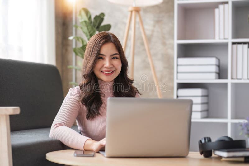 Joven asiática conversando mientras se usa una laptop en casa. videoconferencia en línea de trabajo en casa imagenes de archivo