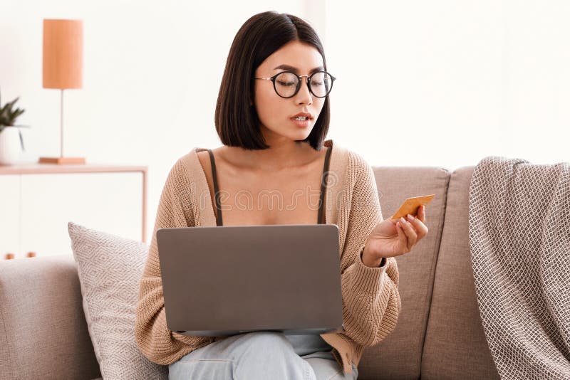 Joven asiática haciendo compras sentada con un pc en el sofá fotografía de archivo