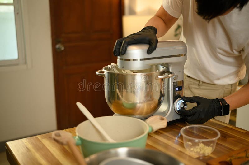 Joven asiático preparando crema batida con una mesa de mezclas en la cocina fotografía de archivo