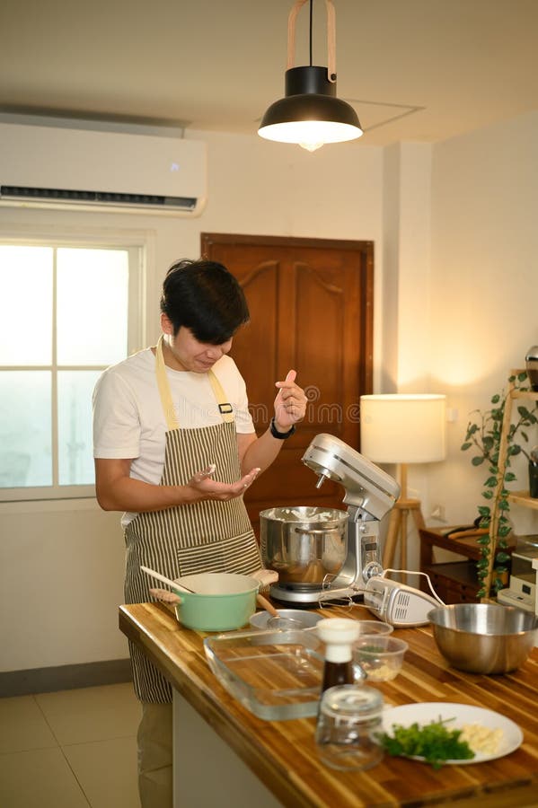Joven asiático usando un mezclador para crema de látigo en una cocina moderna y brillante fotografía de archivo libre de regalías