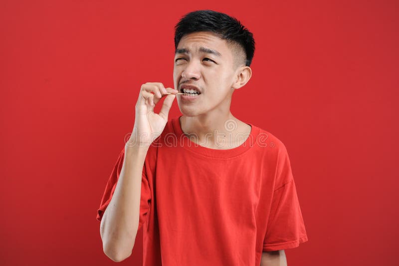 Joven asiático usando un palillo para limpiar su diente. vida saludable joven asiático
