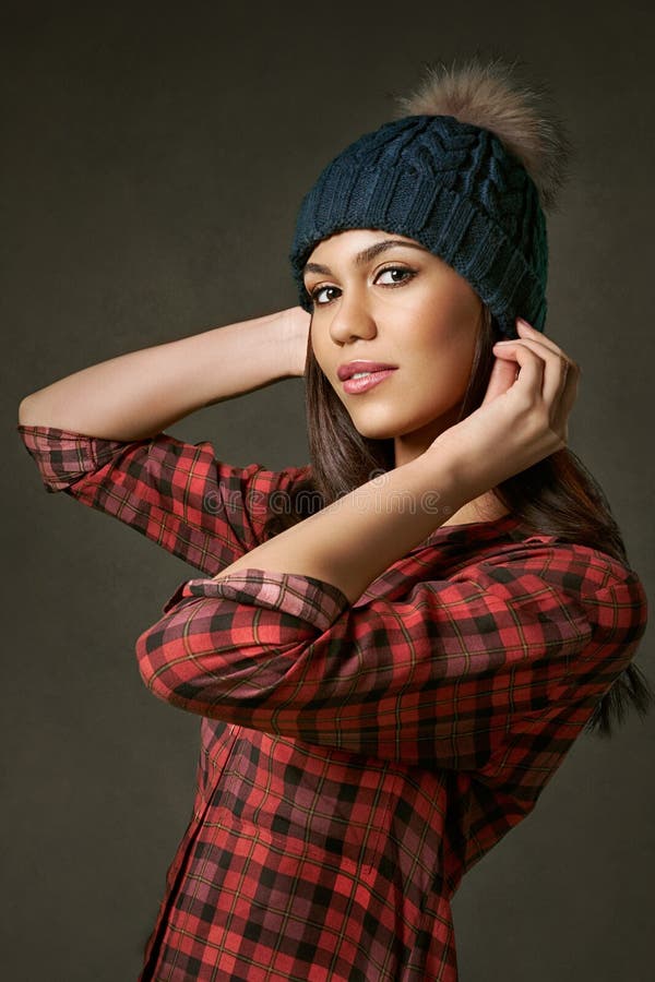 Joven, atractivo, mujer en una camisa de tela escocesa que ajusta un sombrero del invierno imagen de archivo libre de regalías Joven, atractivo, mujer en una camisa de tela escocesa que ajusta un sombrero del invierno imagen de archivo libre de regalías