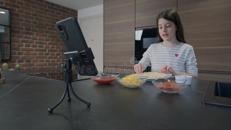 Joven bloguera de comida mostrando una pasta de pizza mientras transmite un video en vivo en su canal almacen de video