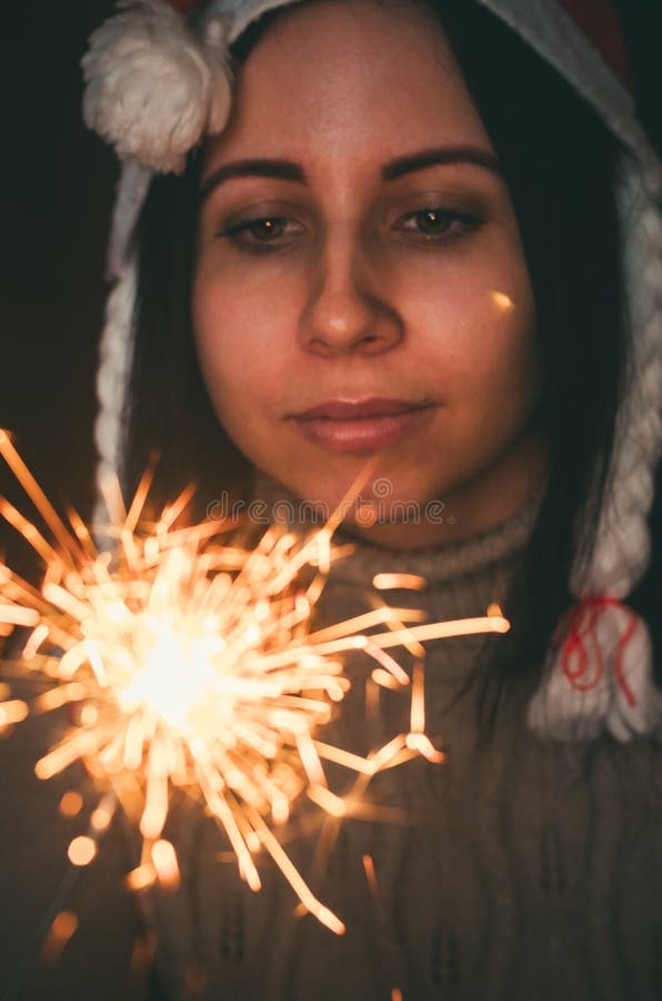 Joven caucásica con el sombrero santa claus sostiene a un chispeante Retrato de Navidad de primer plano imágenes de archivo libres de regalías