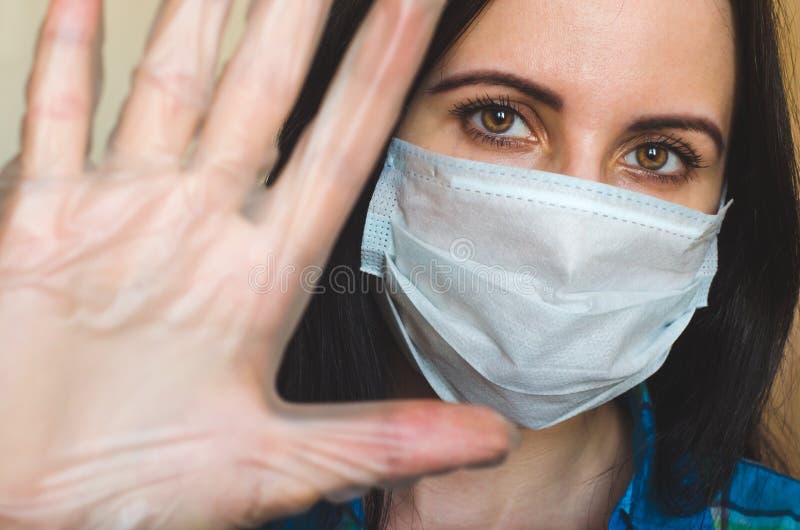 Joven caucásica con máscara facial de protección antivirus muestra el gesto parado como un concepto de distanciamiento social con imagenes de archivo