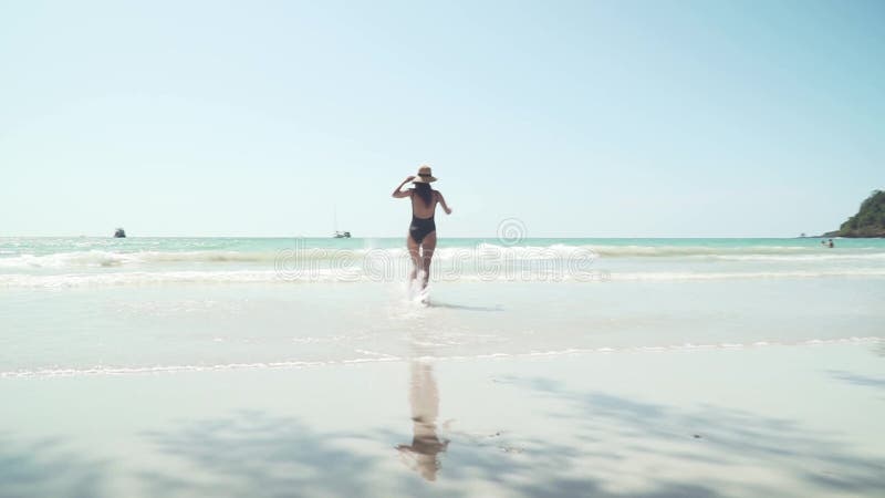 Joven caucásica corre alegremente al agua del mar