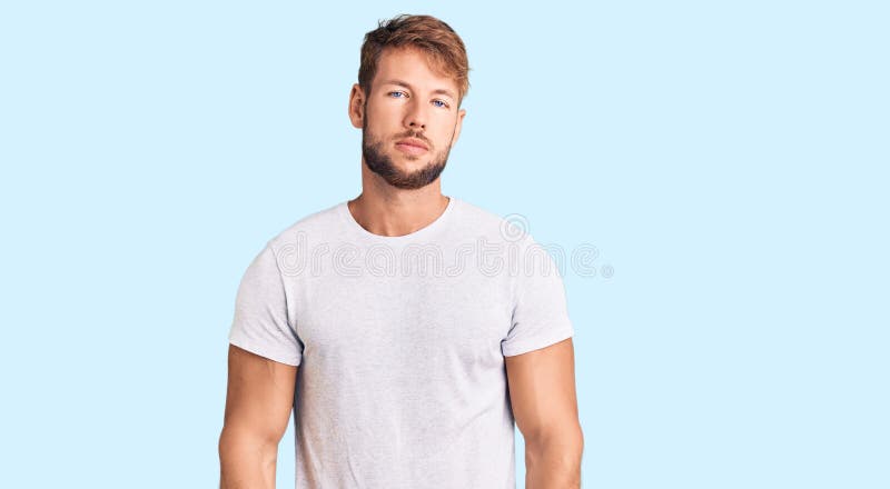 Joven caucásico con camiseta blanca casual relajado con expresión seria en la cara imagen de archivo libre de regalías