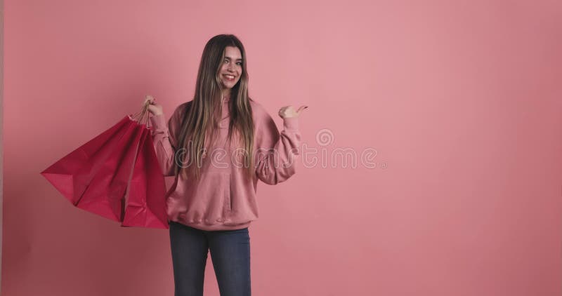 Joven con bolsas de compras apuntando a almacen de metraje de vídeo