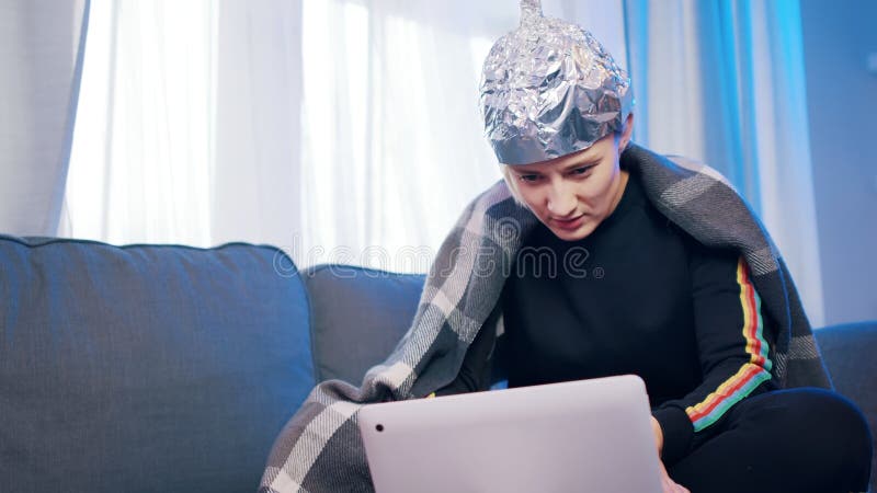 Joven con sombrero de aluminio reaccionando mal en el post de teoría de la conspiración sobre microondas 5g y conexión covid19 imagen de archivo libre de regalías