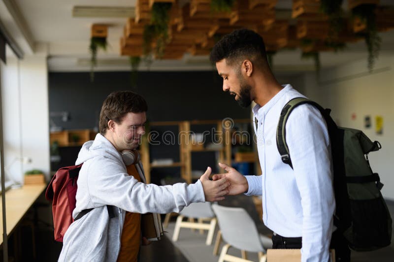 Joven con síndrome de Down saludando a su profesor en la escuela. imágenes de archivo libres de regalías