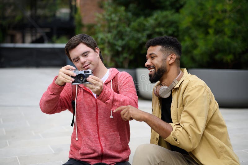 Joven con síndrome de Down y un amigo mentor que pasa tiempo juntos usando una cámara al aire libre. imagenes de archivo