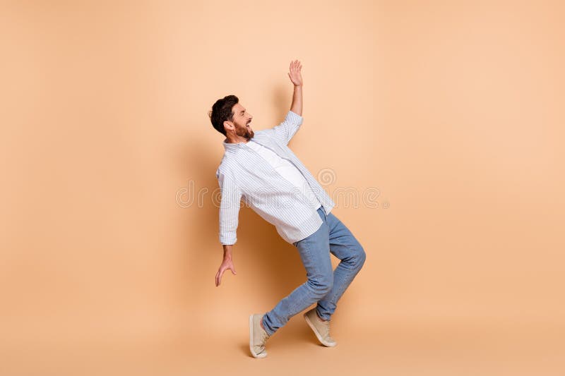 Joven con un estilo casual y elegante, balanceando con gestos expresivos en un fondo beige capturando el movimiento imágenes de archivo libres de regalías