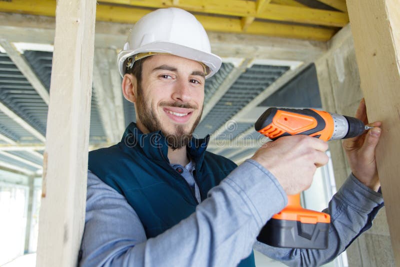 Joven constructor usando taladro inalámbrico imagenes de archivo