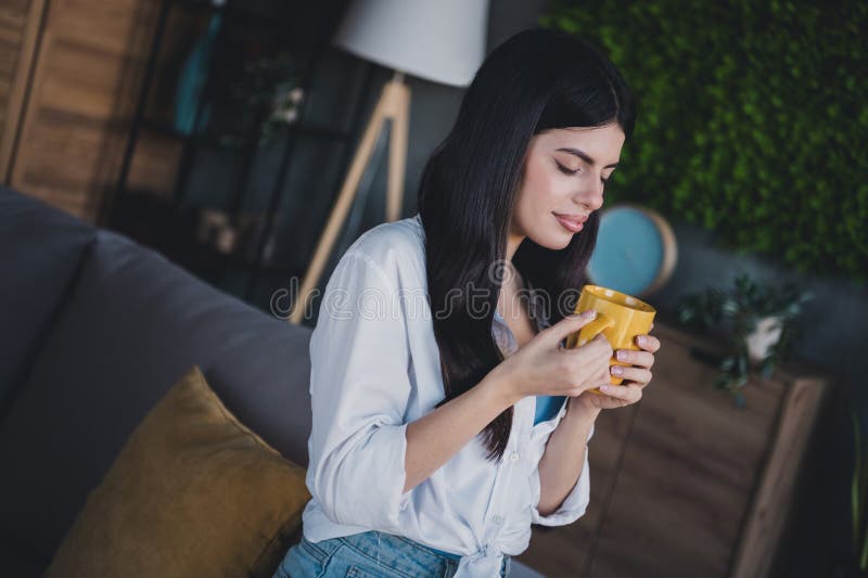 Joven disfrutando de un momento pacífico en casa con una taza de té imagenes de archivo