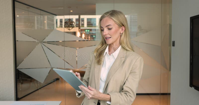 Joven empresaria rubia ocupada usando tablet en la oficina metrajes