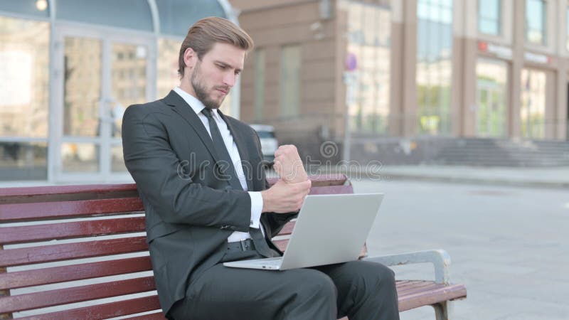 Joven empresario con dolor de muñeca usando laptop sentada en el banco imágenes de archivo libres de regalías
