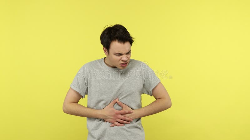 Joven enfermo sintiendo doloroso calambre en el estómago sufriendo fuerte dolor abdominal almacen de video