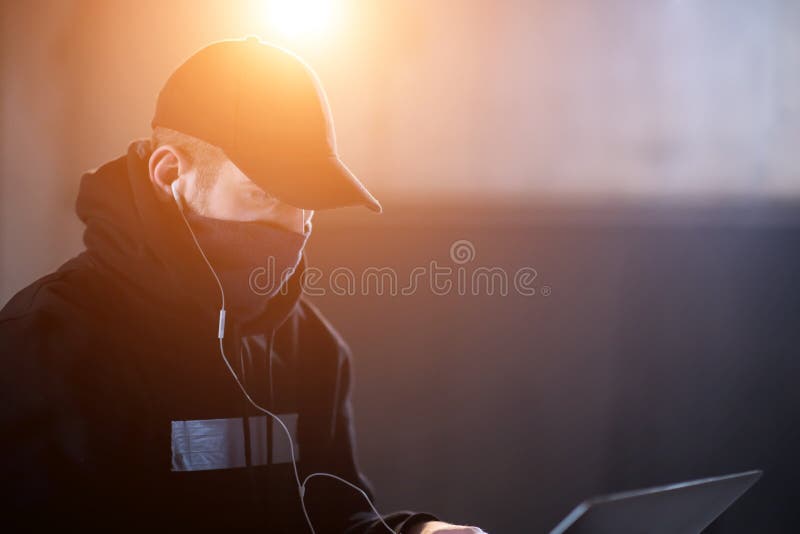 Joven hacker talentoso que usa computadora portátil mientras trabaja en oficinas oscuras foto de archivo
