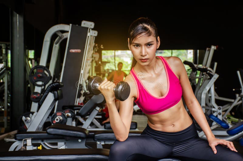 deportista en forma asiática sonriendo y haciendo ejercicio con pesas con  pesas en el gimnasio. mujer