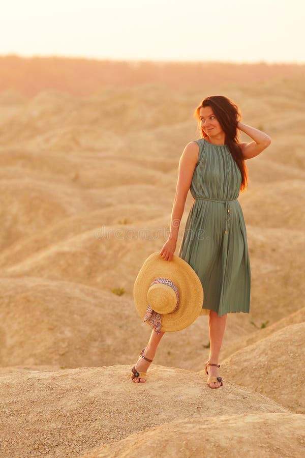 Joven Hermosa Mujer Sonriente Con Pelo Largo En Vestido Azul Con Sombrero De Paja En La Mano De Pie En La Arena En El Desierto Al Imagen de archivo - Imagen de Joven Hermosa Mujer Sonriente Con Pelo Largo En Vestido Azul Con Sombrero De Paja En La Mano De Pie En La Arena En El Desierto Al Imagen de archivo - Imagen de