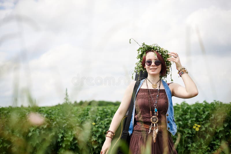 Joven Hippie De Pelo Corto Rojo, Vestido Con Ropa De Boho, Gafas De Flores, De Pie En Un Campo Verde, Sosteniendo Foto de archivo Imagen de campo, creativo: