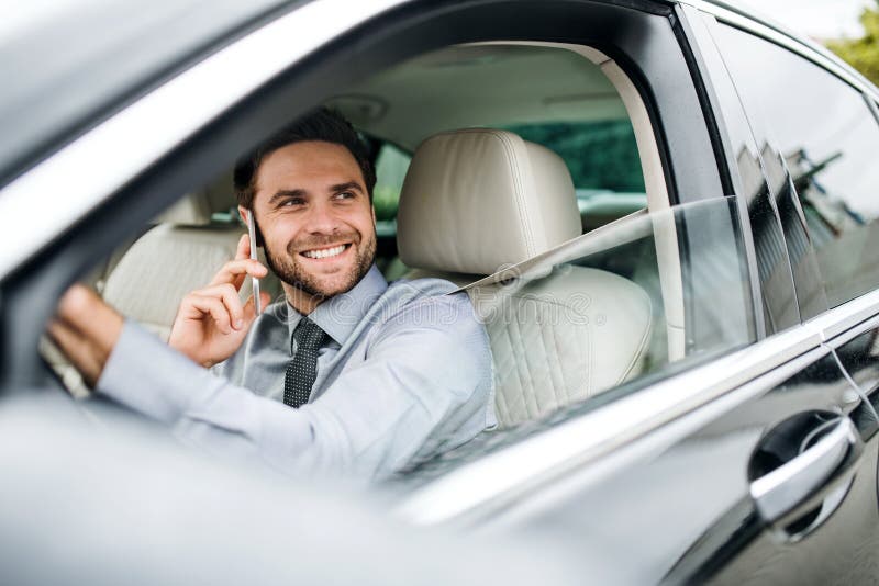 Joven hombre de negocios con camisa, corbata y smartphone sentado en un coche fotos de archivo libres de regalías Joven hombre de negocios con camisa, corbata y smartphone sentado en un coche fotos de archivo libres de regalías