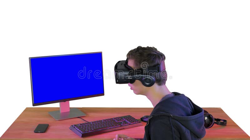 Joven jugador con casco de realidad virtual sentado en la mesa sobre fondo blanco. almacen de video