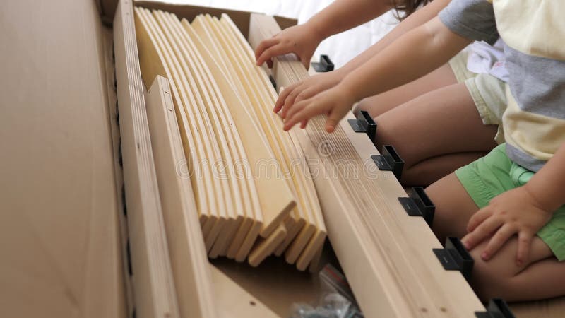 Joven madre soltera con hijos mirando el contenido de las cajas para la futura cama en el dormitorio de los niños. interior