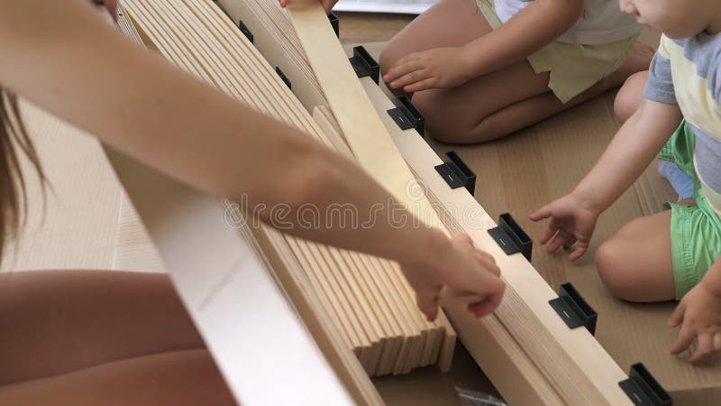 Joven madre soltera con hijos mirando el contenido de las cajas para la futura cama en el dormitorio de los niños. interior