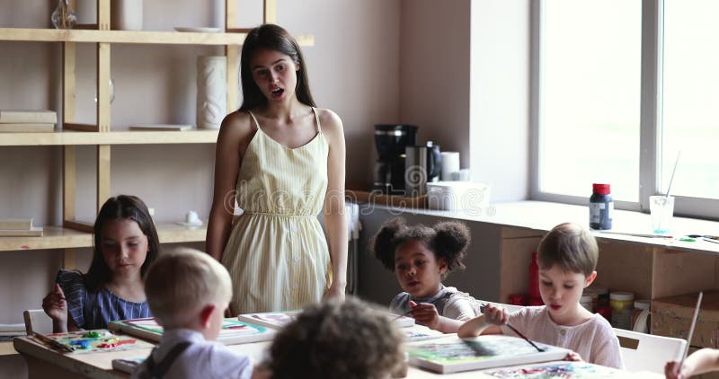 Joven maestra artística enseñando a niños pequeños en el estudio almacen de video