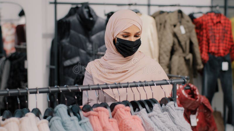 Joven Mujer árabe Compra Con Máscara De Protección Médica Elige Ropa En Tienda De Ropa De Venta Al Menor Compra Imagen de archivo - de higiene, cambiar: 250903823