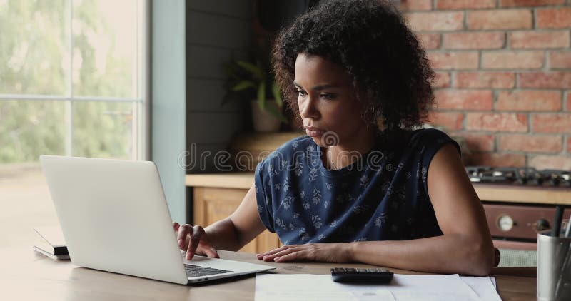 Joven mujer africana paga cuentas en línea suma de cheque en calculadora